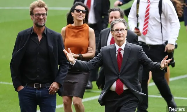Juergen Klopp (L), directeur de Liverpool, s'entretient avec le propriétaire John W. Henry lors de l'ouverture du stand nouvellement construit au club de football de Liverpool' title='Les fans de Liverpool impressionnés par le dévoilement de la tribune principale d'Anfield